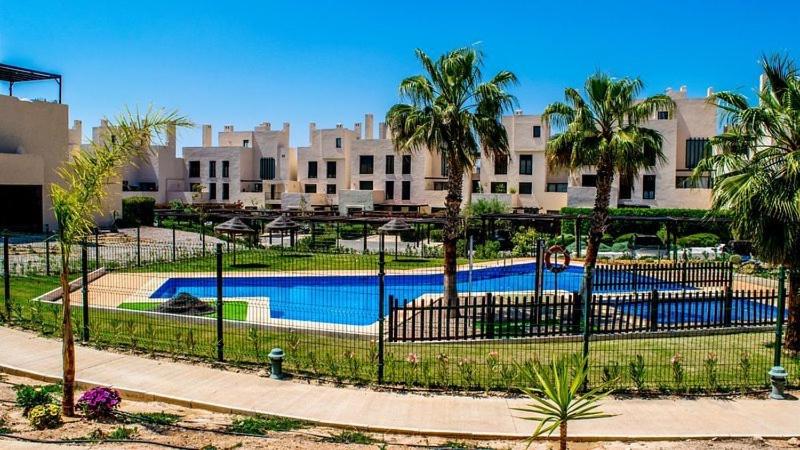 ein Zaun mit einem Swimmingpool vor einem Gebäude in der Unterkunft Corvera Golf Lexu in Corvera