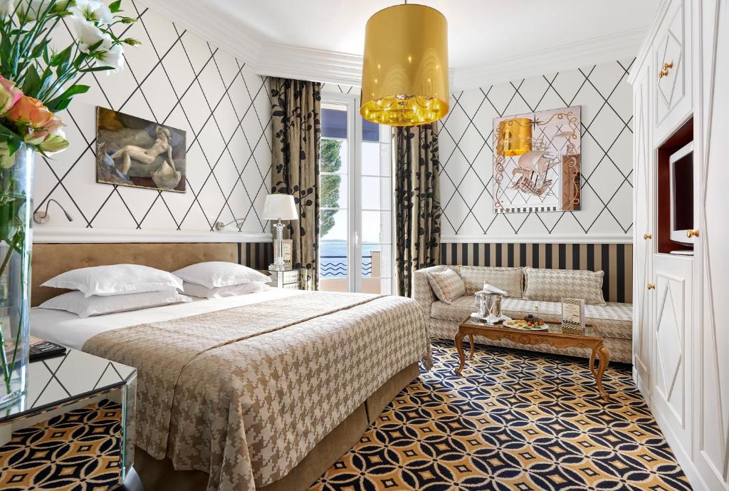 a hotel room with a bed and a couch at Hôtel Belles Rives in Juan-les-Pins