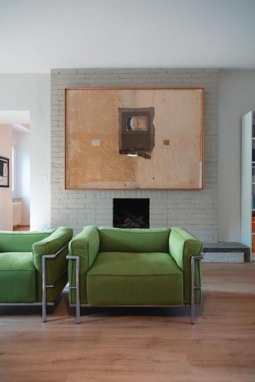 a living room with two green couches and a fireplace at Cottage di design con giardino in Bosco Marengo