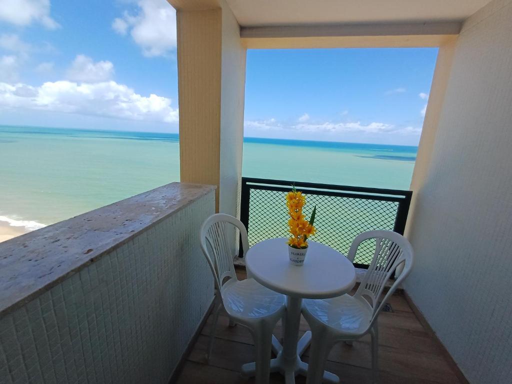 ein Tisch und Stühle auf einem Balkon mit Blick auf das Meer in der Unterkunft Flat Costa Mar in Recife