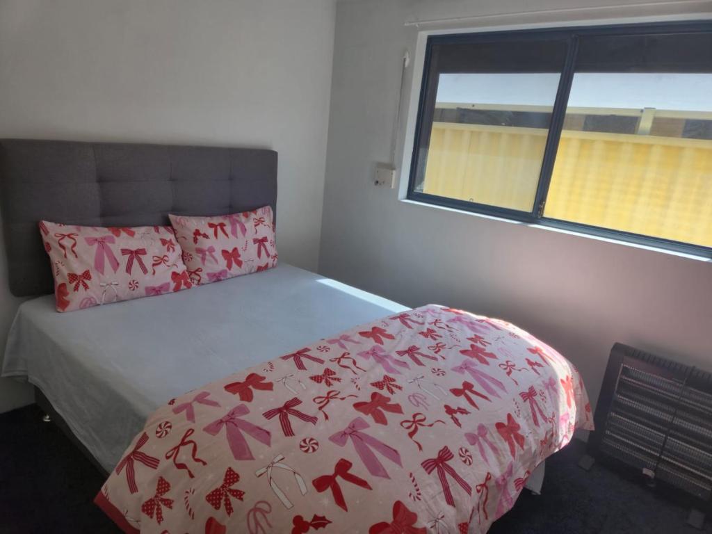 班伯里Dalyellup 2BR Accommodation-Entire rear Unit-Walkable to major Supermarkets的一间卧室配有一张带粉红色棉被的床和窗户