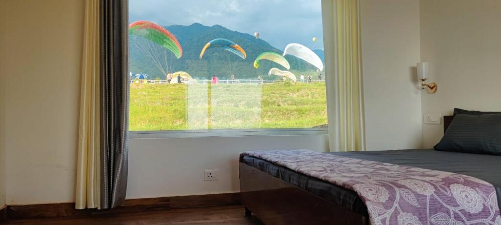 a bedroom with a window with a view of parrots at Sunshine Cottages in Bīr