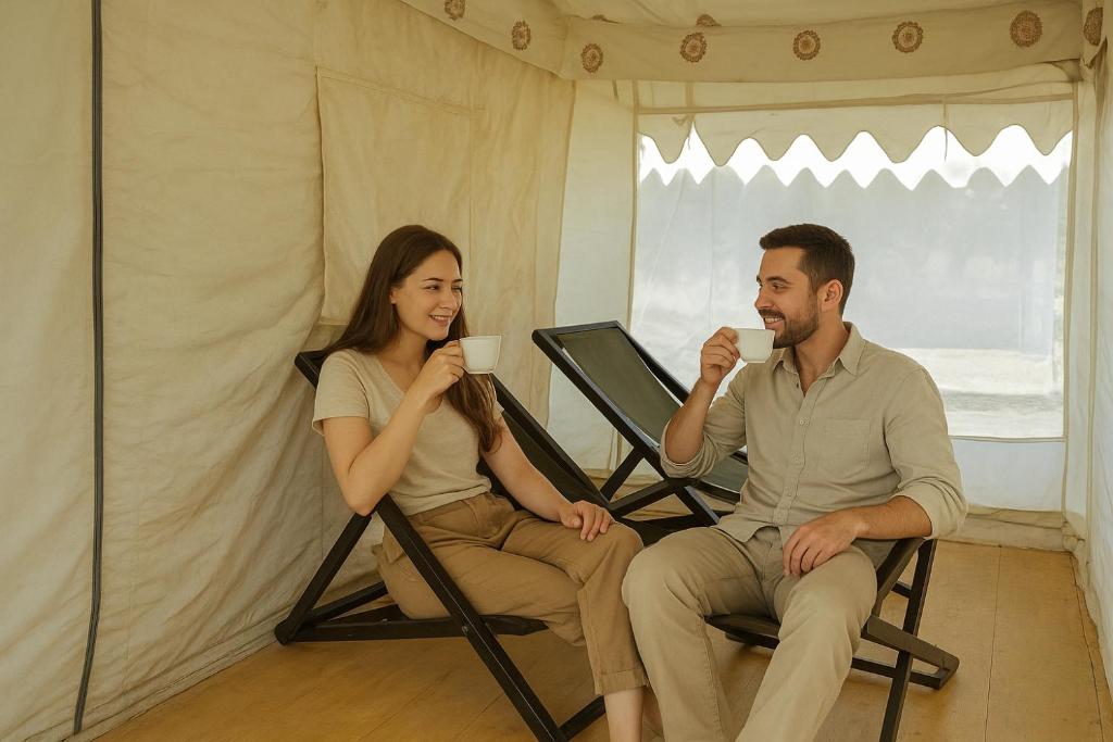 斋沙默尔desert Galaxy Camp Jaisalmer的一男一女坐在椅子上喝咖啡