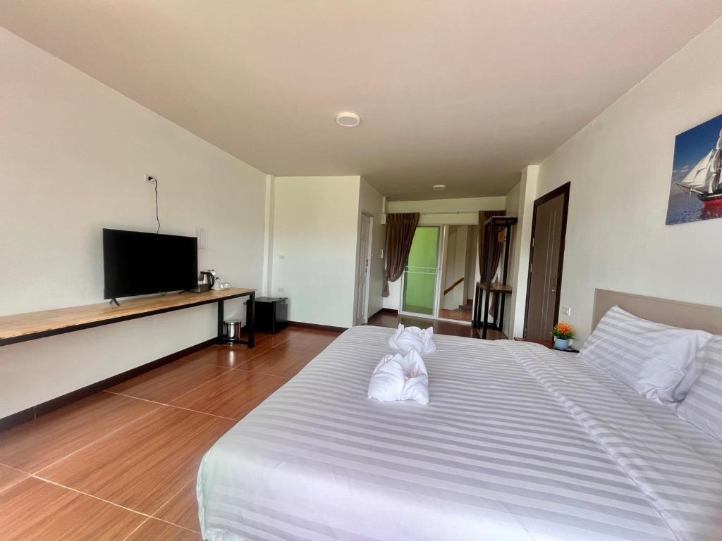 - une chambre avec un grand lit blanc et une télévision à écran plat dans l'établissement Lucky 9 Airport Hotel Phuket, à Nai Yang Beach