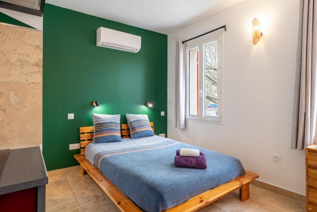 ein Schlafzimmer mit einem Bett und einer grünen Wand in der Unterkunft L'étape Arlésienne in Arles