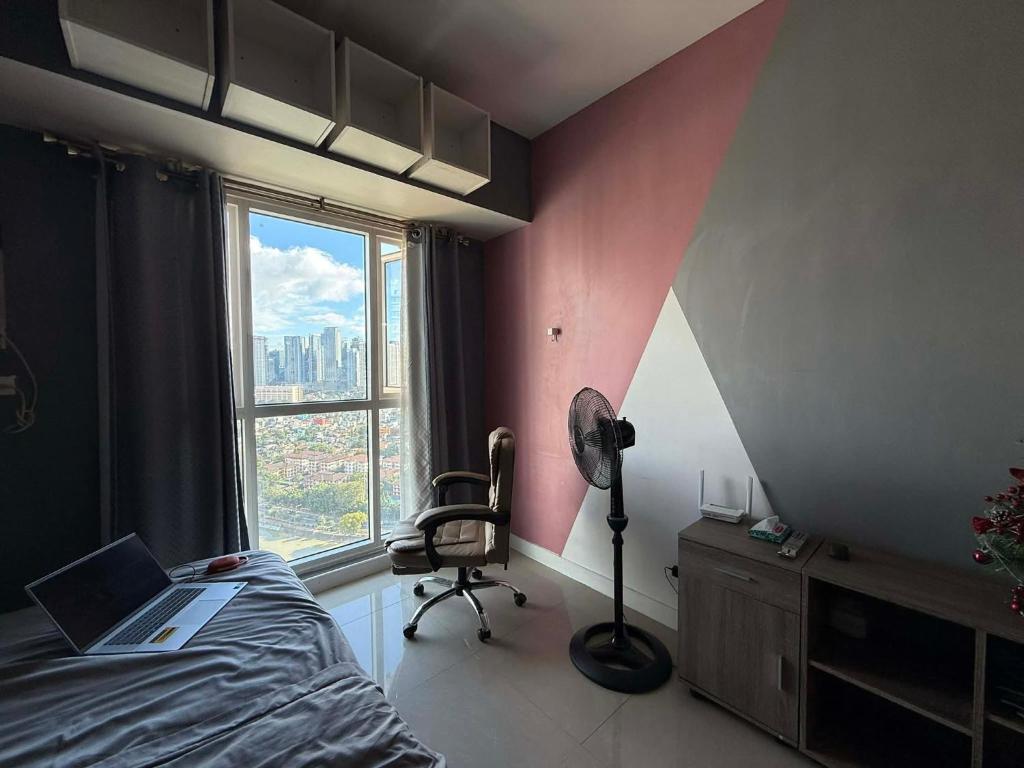 ein Schlafzimmer mit einem Bett, einem Stuhl und einem Fenster in der Unterkunft Staycation in Buli Muntinlupa in Manila