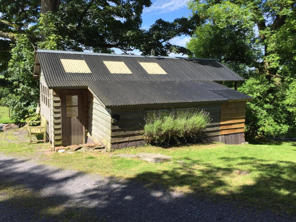 uma pequena cabana de madeira com um telhado preto em Faraway Follies em Llandegla