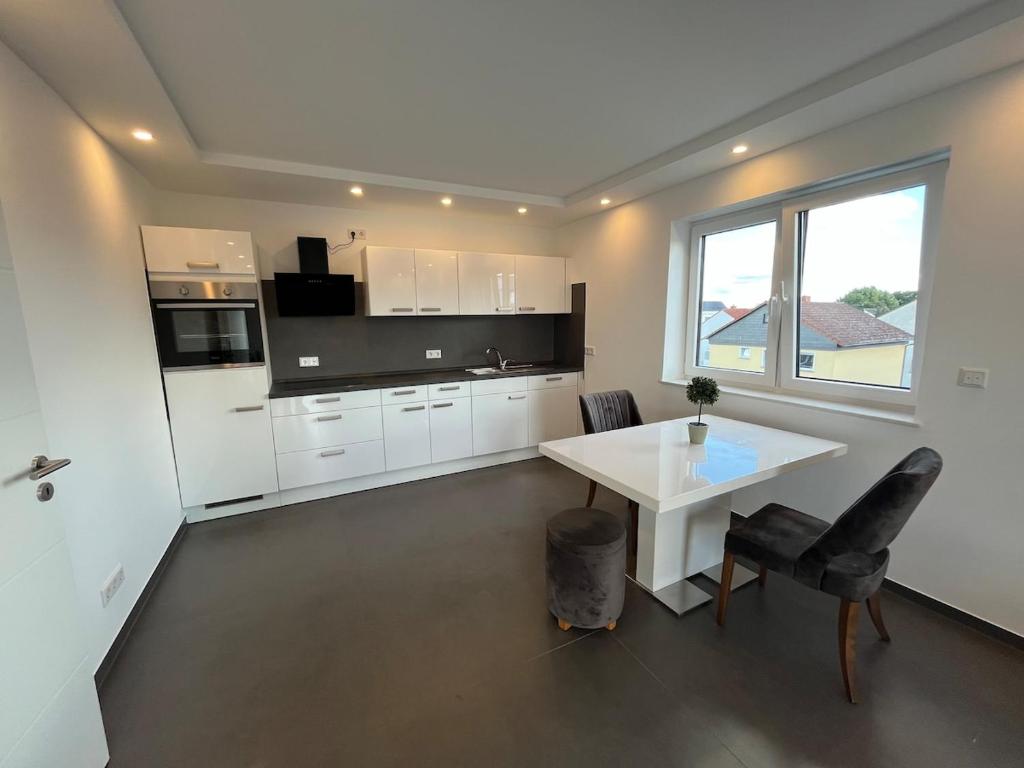 a kitchen with white cabinets and a white table at Modern new-build apartment in Groß-Gerau
