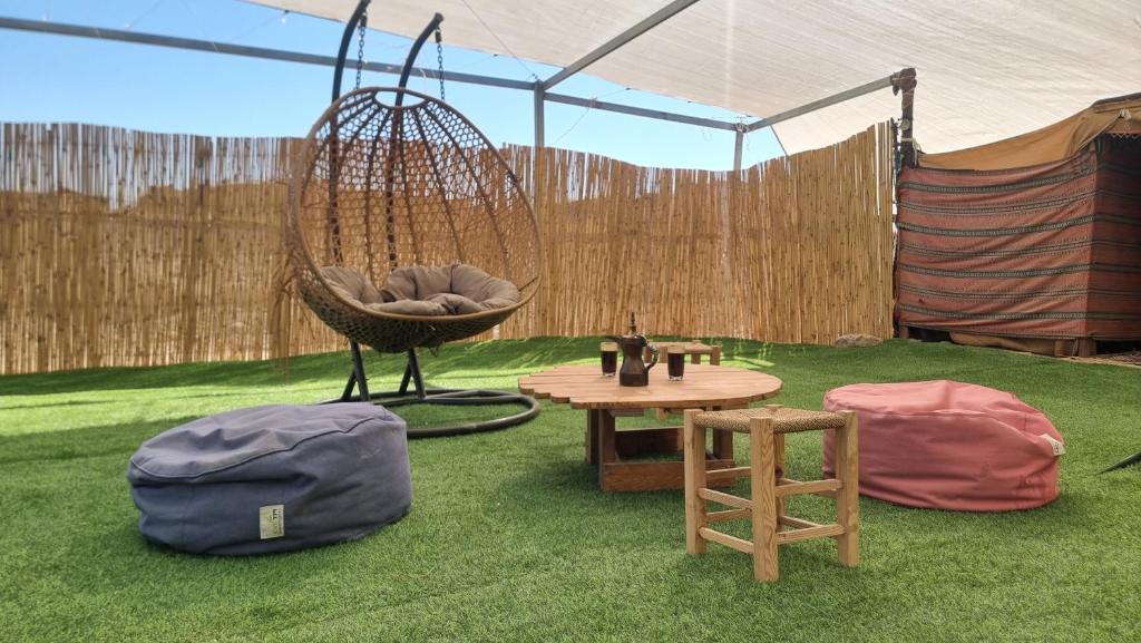 a tent with a hammock and a table and a chair at Khan Yaelim in Arad