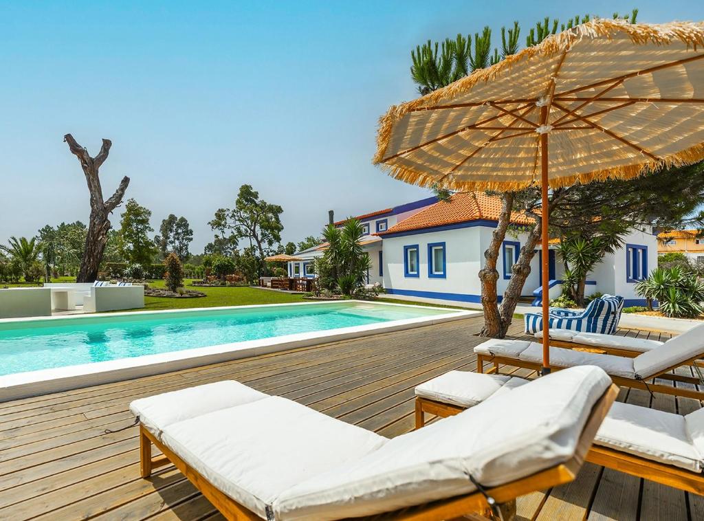 a deck with chairs and an umbrella next to a swimming pool at Almaa da Ria in Ílhavo
