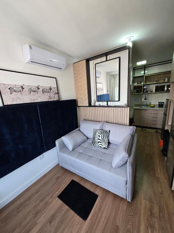 a living room with a couch and a mirror at Polo NEXT Studios in Volta Redonda