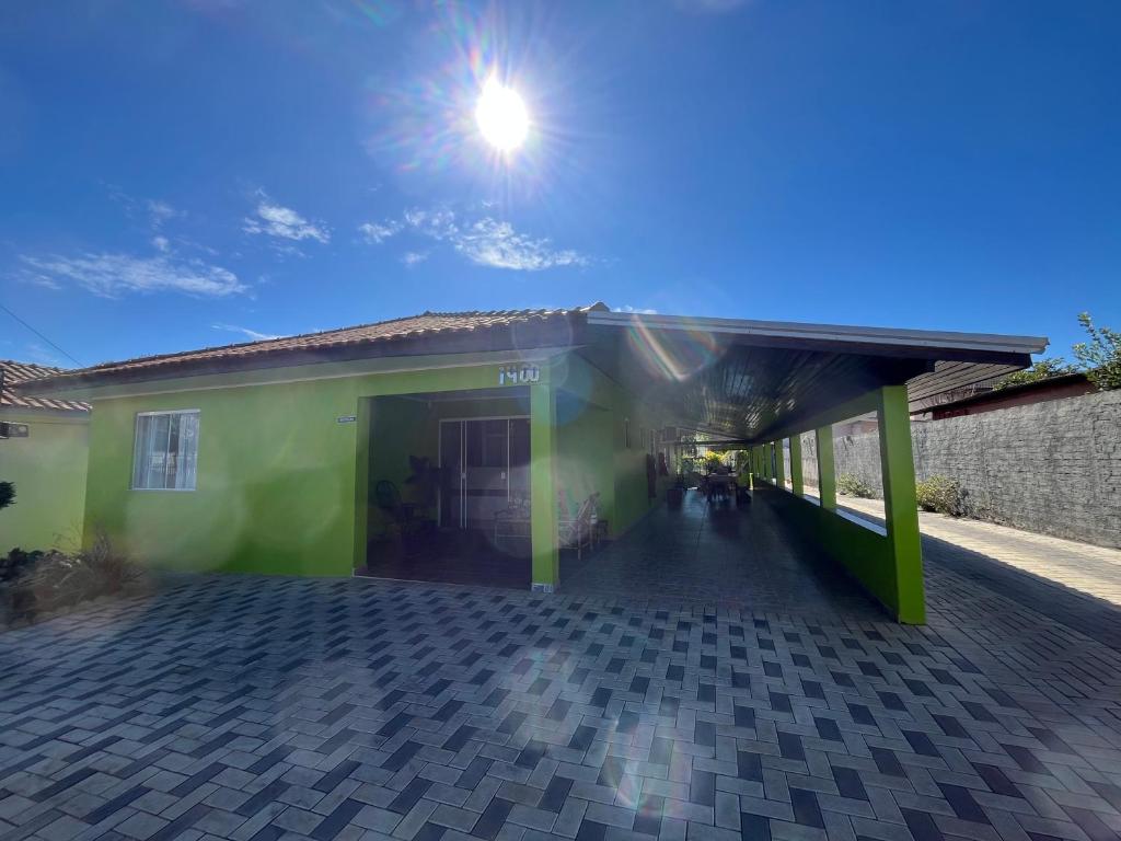 un bâtiment vert avec le soleil dans le ciel dans l'établissement Pousada Avenida, à Tibagi