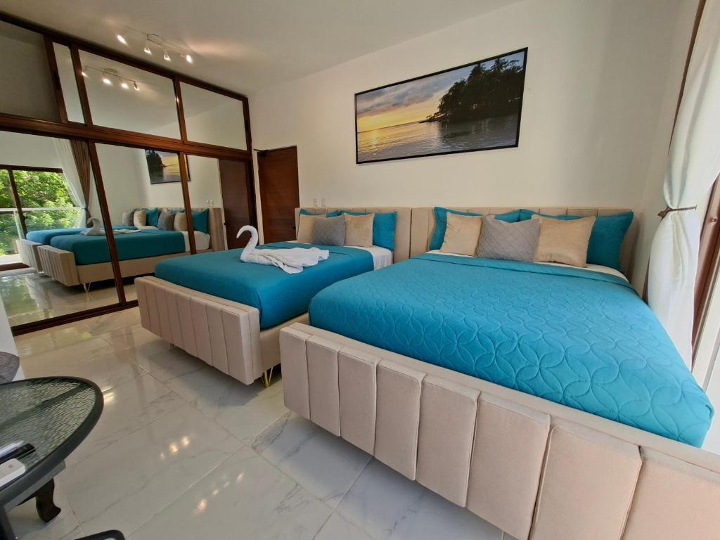 two beds in a hotel room with blue beds at Hermosa villa familiar cucu's home beach in Río San Juan