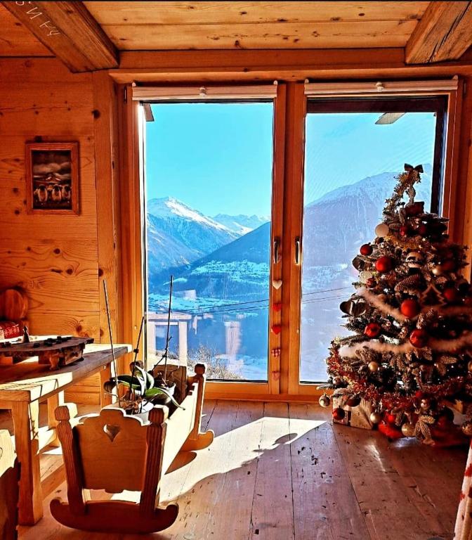 a room with a christmas tree in front of a window at Appartement Valaisan typique in Guttet-Feschel