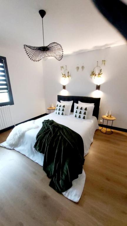 una camera da letto con un letto bianco con una coperta nera di L'Orée des Champs a Magny-Fouchard