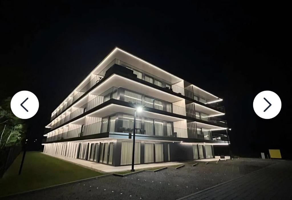 a tall building at night with two circles in front of it at Sea and lake apartament in Mielno