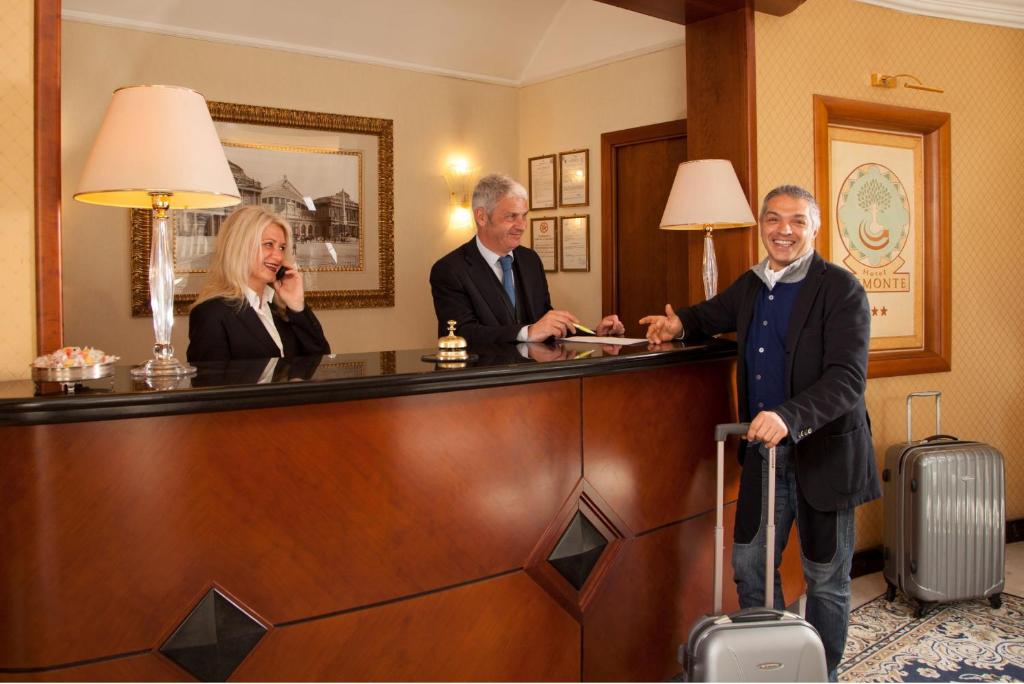 three people standing at a reception desk in a hotel room at Hotel Piemonte in Rome