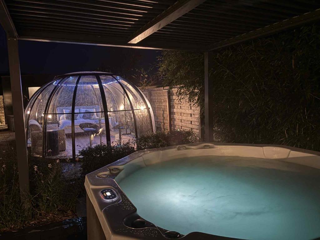 a hot tub in a backyard with a gazebo at Dôme du puits avec jacuzzi et sauna privatif in Havinnes