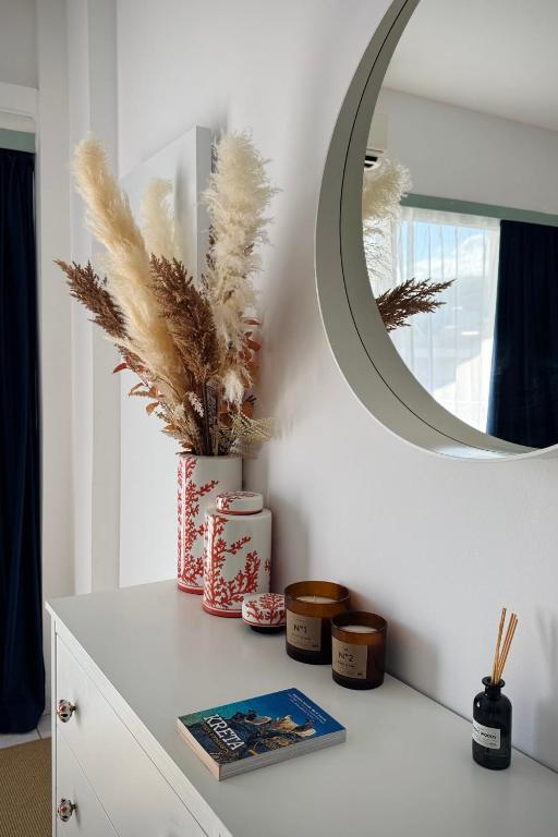 a white dresser with a mirror and a book at Green Sea Studio in Rethymno
