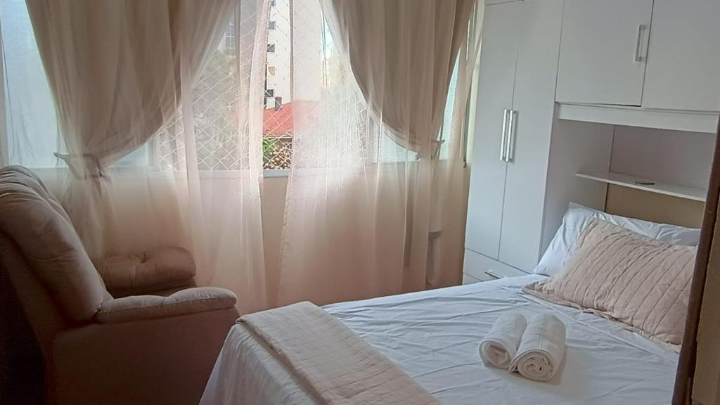 ein Schlafzimmer mit einem Bett und einem Stuhl und einem Fenster in der Unterkunft Quarto ao lado da praça da Liberdade in Belo Horizonte