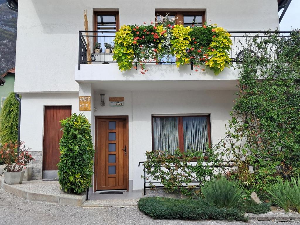 una casa blanca con un balcón con flores y una puerta en Apartment Norma, en Bovec
