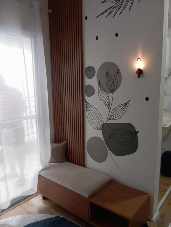 a room with a chair and a wall with a flower mural at Apartamento frente ao mar com piscina, a 5 minutos da Cachoeira 1 quarto in Mongaguá