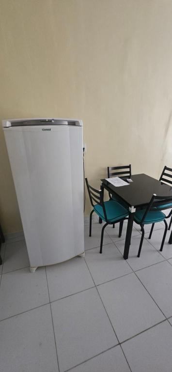 ein weißer Kühlschrank neben einem Tisch und Stühlen in der Unterkunft Meu lugar! in Manaus