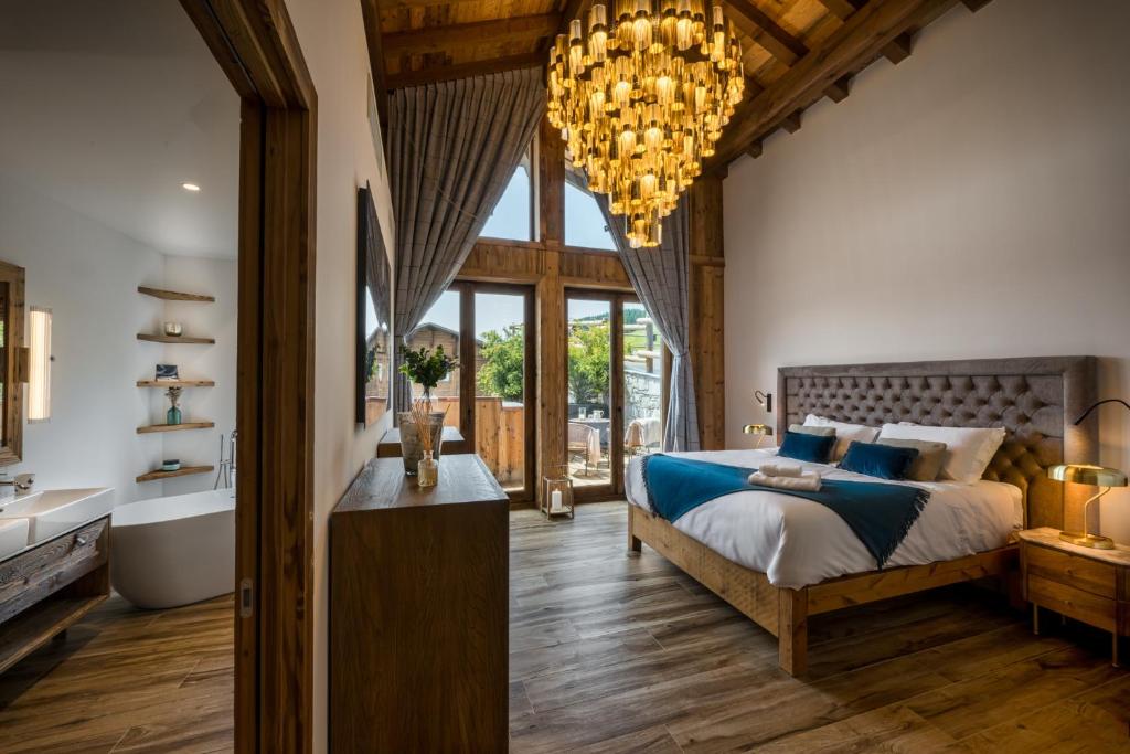 a bedroom with a large bed and a chandelier at ULTIMATE Les Gets Luxury - Above the Clouds with Sauna, Pool etc - Mansion Ensolielle for 15 in Les Gets