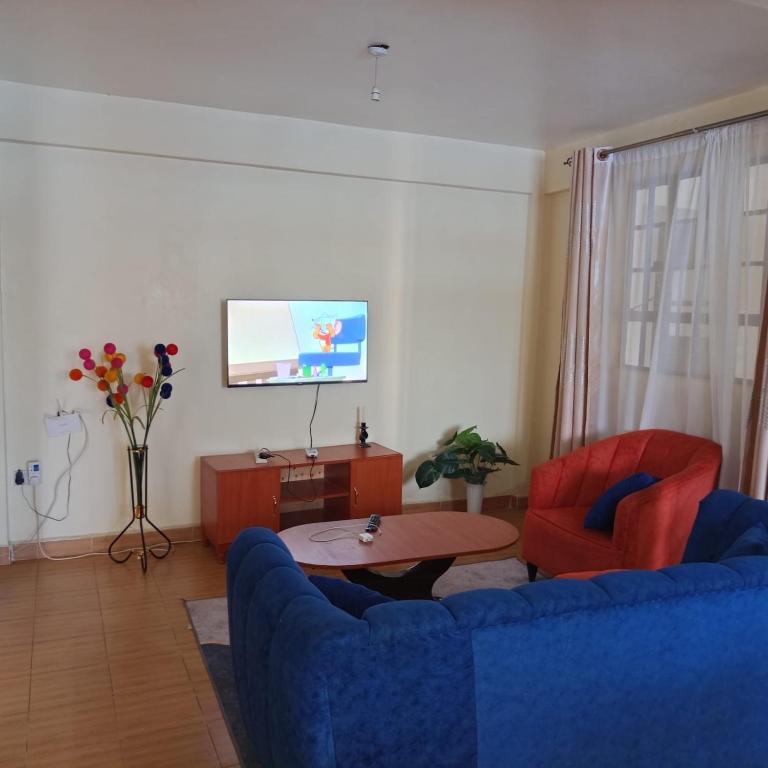 Amani -Zuriel homes 2 Bedroom Apartment في Kakamega: غرفة معيشة مع كرسيين ازرق وتلفزيون