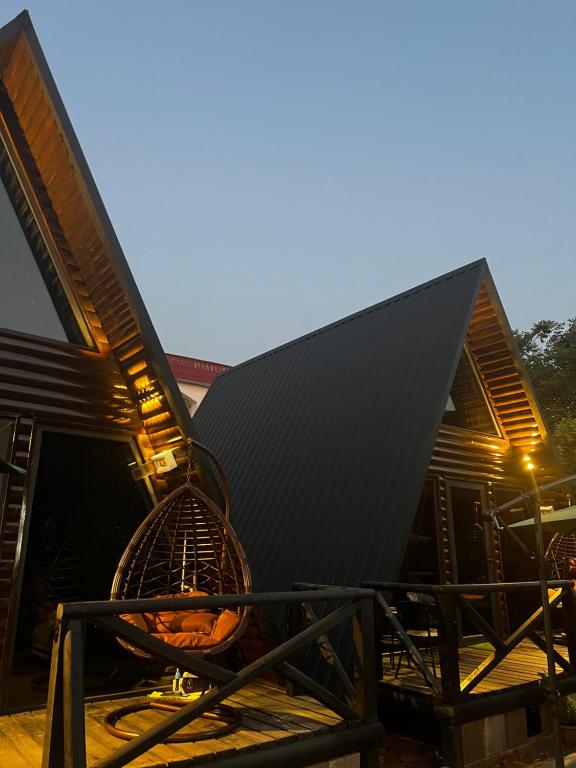 une maison avec un toit noir et des chaises sur une terrasse dans l'établissement Sweet Cottage, à Kobuleti
