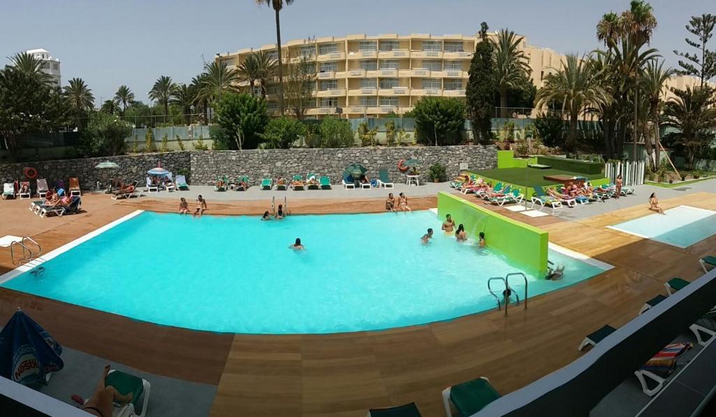 a large swimming pool with people in a resort at Apartamentos Los Aguacates in Playa del Ingles