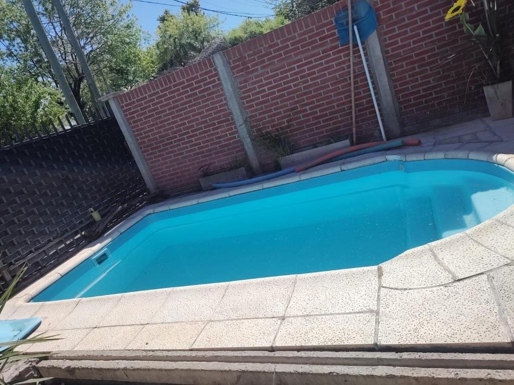 a large blue swimming pool next to a brick wall at quinta la peke in Ituzaingó