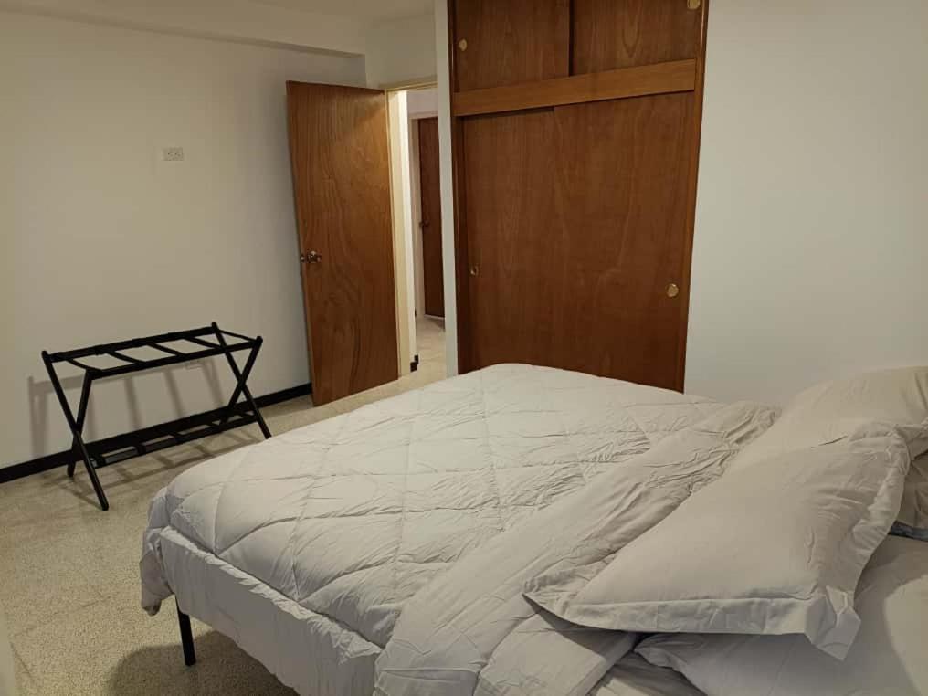 a bedroom with a large bed and a wooden cabinet at Apartamento Remodelado 2 Habitaciones en la Mejor Zona del Centro de Caracas in Caracas