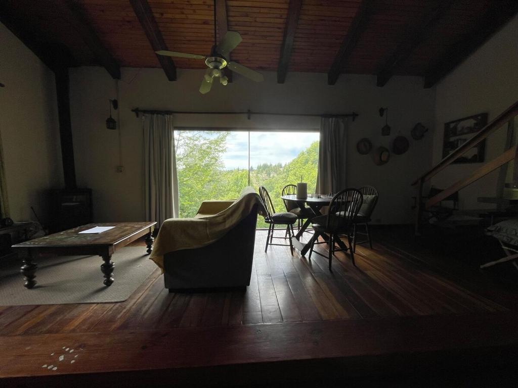 ein Wohnzimmer mit einem Tisch und Stühlen sowie einem großen Fenster in der Unterkunft Casa Familiar in La Cumbrecita