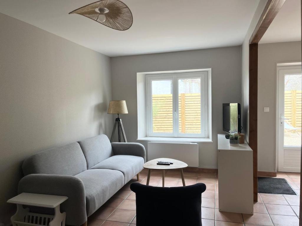 a living room with a couch and a tv at Le Bas des Landes Gîte in Pléneuf-Val-André