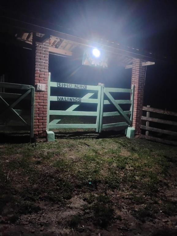 a gate to a barn at night with a light at Chalé alto valinhos in Itamonte