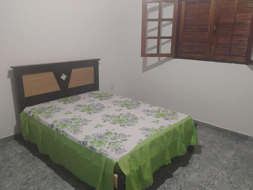 una camera da letto con un letto con una coperta verde e una finestra di Chalé alto valinhos a Itamonte