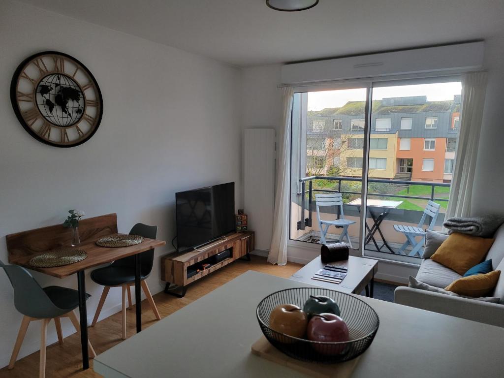 un soggiorno con una grande finestra e un tavolo di Les voiliers a Courseulles-sur-Mer