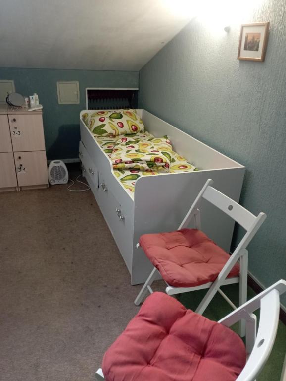 Un pequeño dormitorio con una cama y una silla. en Мансарда- укриття поруч, 10 метрів, en Kiev