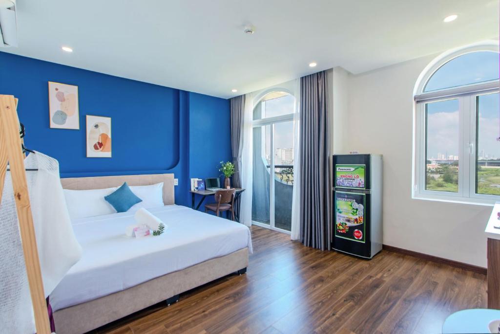 une chambre avec un lit blanc et un mur bleu dans l'établissement Fusia Hotel & Apartment, à Đà Nẵng