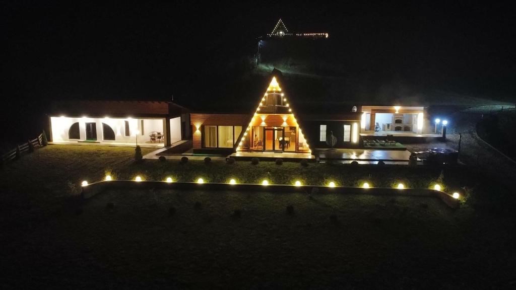 a house with lights in the yard at night at Cabana A-frame Apuseni in Burzeşti
