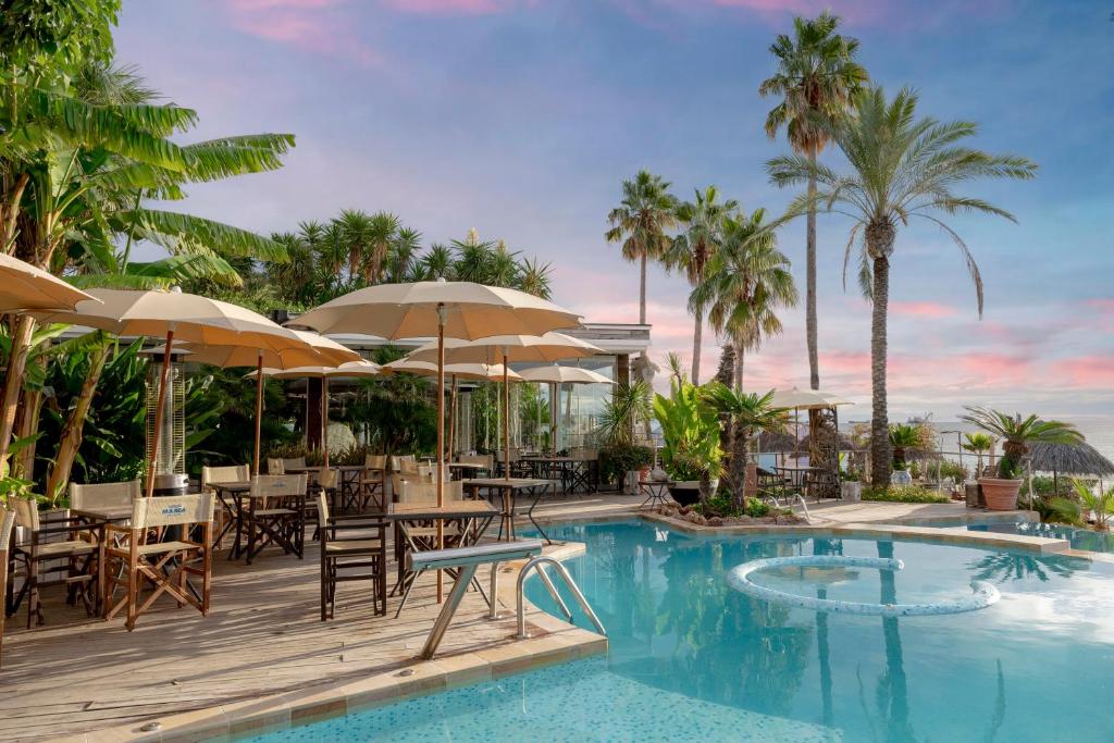 una piscina en un resort con mesas y sombrillas en Mare Hotel, en Savona