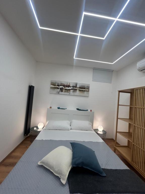 ETNA HOUSE LUXURY con giardino e vasca idromassaggio في لينغواغلوسا: غرفة نوم بسرير ابيض كبير ومخدة زرقاء