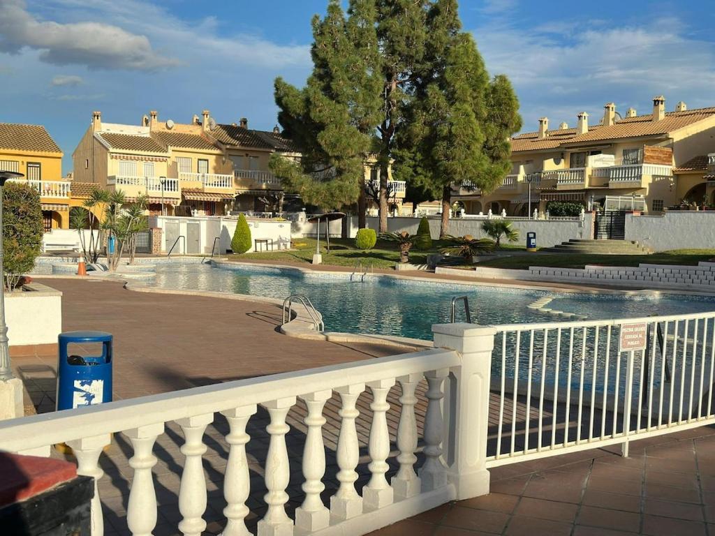 einen Pool mit einem weißen Zaun und Häusern in der Unterkunft Casa Sol y Paz in El Campello