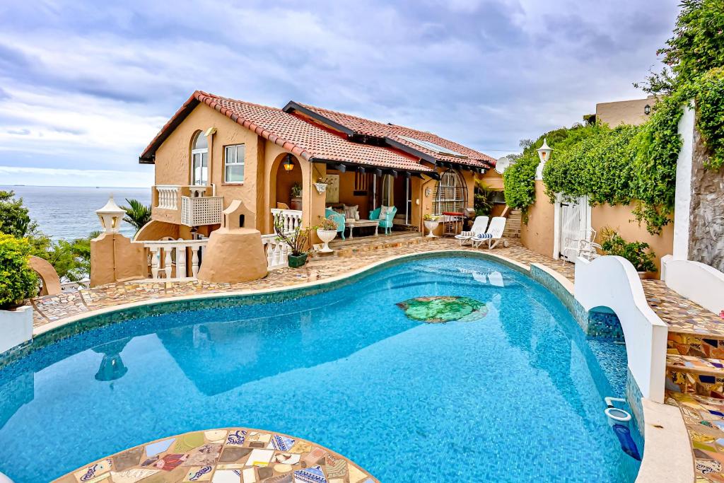 a house with a swimming pool in front of the ocean at Villa Bel Fiori - 4 Bedroom Villa in Ballito