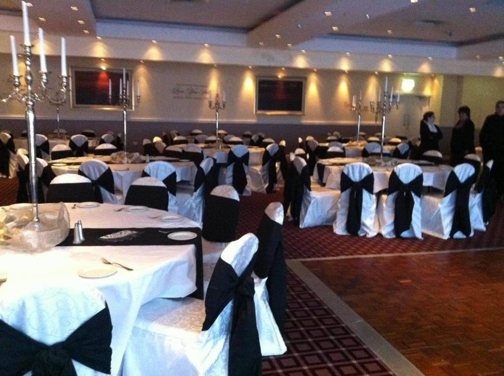 a banquet hall with tables with white and black bows at Ashbourne House Hotel in Ashbourne