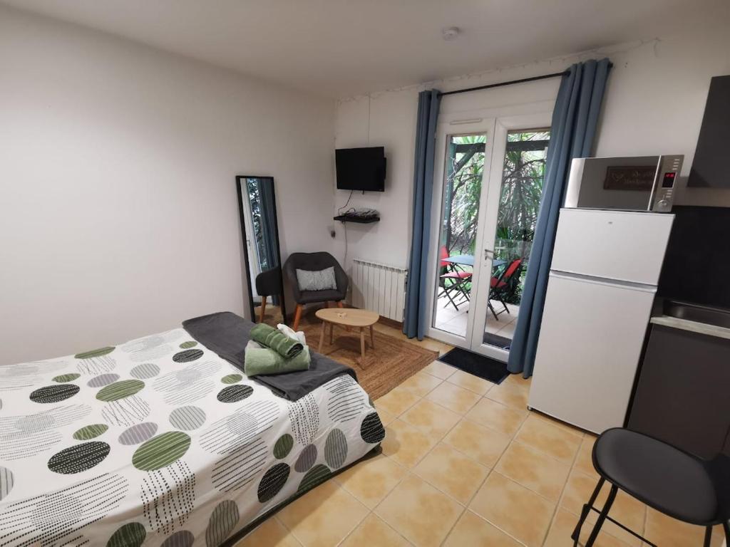 a bedroom with a bed and a kitchen with a refrigerator at Studio Le Yuka entre Mer et Montagne in Villelongue-dels-Monts