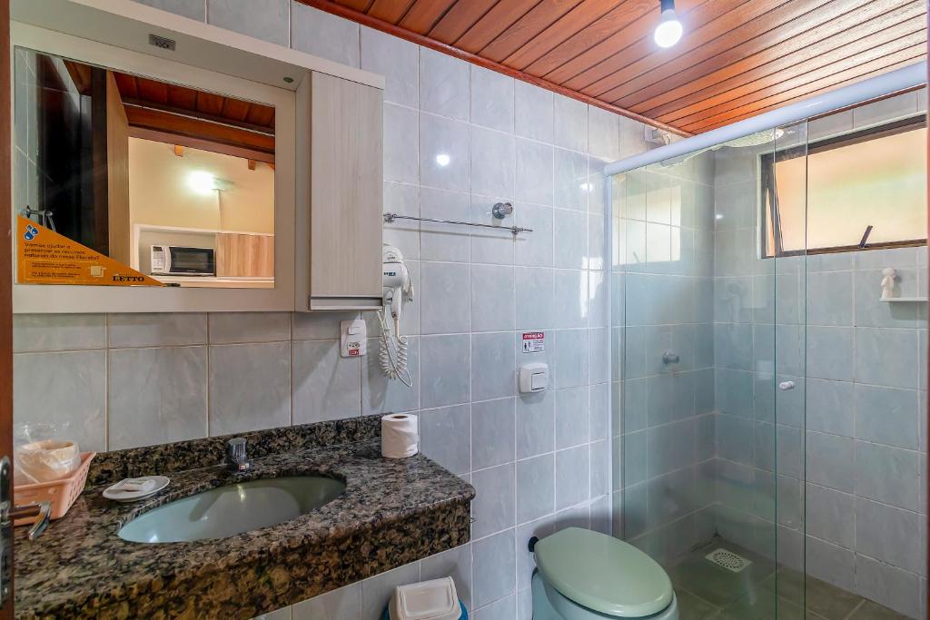 a bathroom with a sink and a toilet and a mirror at Stúdio Jurerê vista Mar in Florianópolis