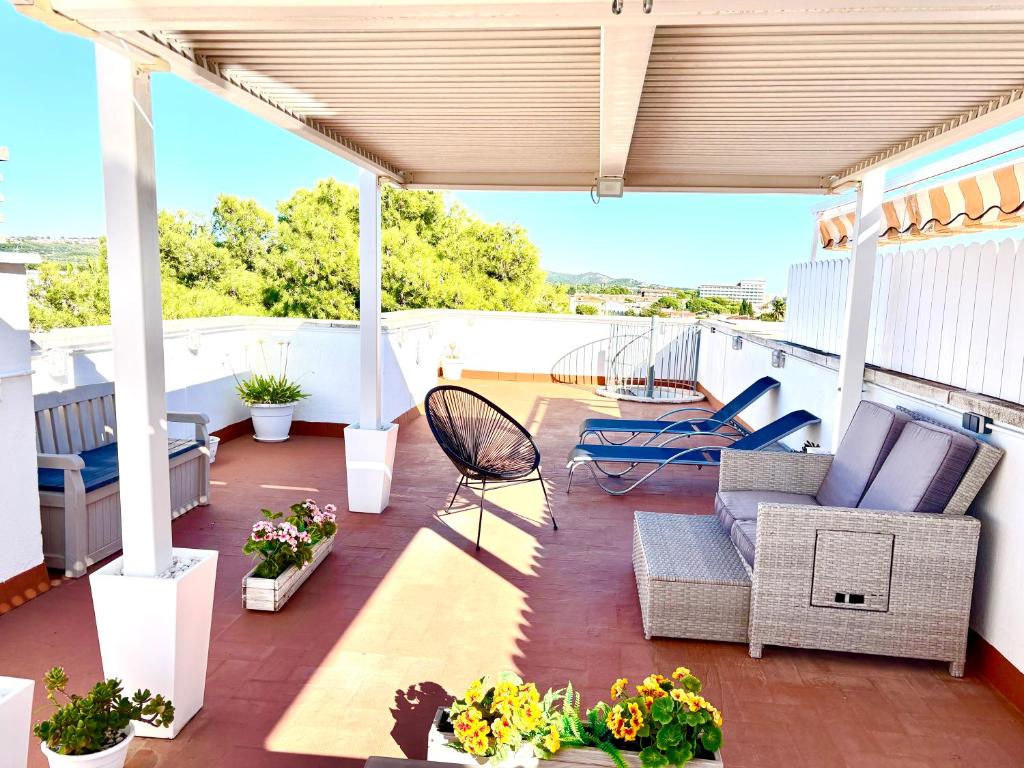 Un patio con un sofá y sillas en un tejado. en TheHavenEscape Penthouse Pool & Sea View near Barcelona, en Comarruga