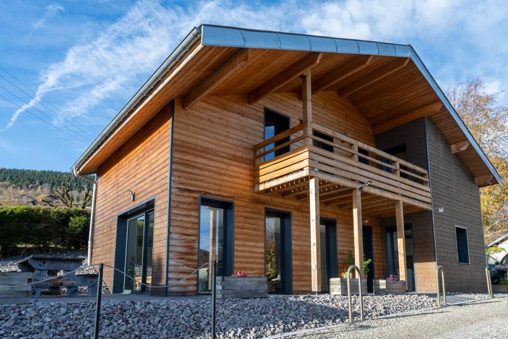 een huis met een houten gevel en een balkon bij Charmant chalet, spacieux, proche du lac, vue sur la montagne in Gérardmer